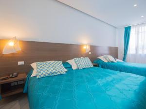 two beds in a hotel room with blue sheets and pillows at Hotel Splendid in Diano Marina