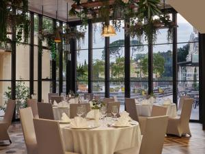 a dining room with white tables and chairs and windows at Hotel Continental in Opatija