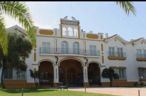 a large white building with a clock tower on it at Las Marismas-Puente del Rey in El Rocío