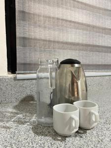 a coffee pot and two cups on a counter at Alona Chrisah Apartelle in Panglao Island