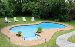 een groot zwembad met stoelen en een tafel bij African Aquila Guest Lodge in Port Elizabeth