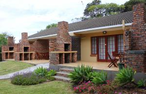 a brick house with a patio and a table at African Aquila Guest Lodge in Port Elizabeth