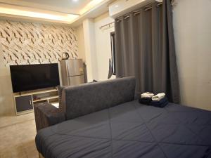a room with a bed and a tv and a couch at Fora Boutique Hotel in Karon Beach