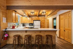 a kitchen with wooden cabinets and a island with bar stools at Chipmunk Lodge by NW Comfy Cabins in Leavenworth