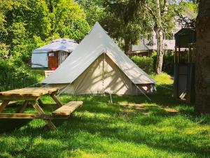 a tent and a picnic table in the grass at Arkeo - Luxury tents and cabins at the river in Nonceveux