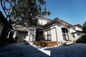 a white house with a tree in front of it at SAUNARF Aoshima in Miyazaki