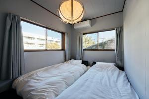 two beds in a room with two windows at SAUNARF Aoshima in Miyazaki