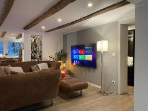 a living room with a couch and a flat screen tv at Sauerland Apartments in Schwalefeld