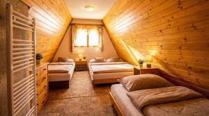 a bedroom with two beds in a room with wooden walls at CHATKA ŠTÔLA in Vyšné Hágy