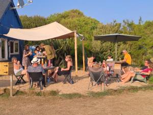 a group of people sitting in chairs under an umbrella at Camping le Kergorz in Plomodiern +11 photos