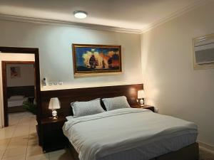 a bedroom with a bed and a painting on the wall at شقة العقيق الأولى in Medina