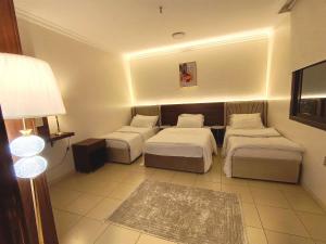 a hotel room with two beds and a lamp at شقة العقيق الأولى in Medina