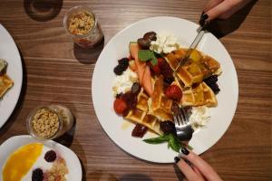 a plate of waffles and fruit on a table at Liebeskind Boutique Hotel Old Town in Krakow