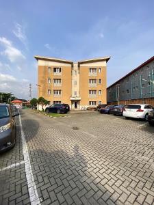 a parking lot with cars parked in front of a building at Modern 2-Bedroom Secure Apartment in Surulere in Suru Lere