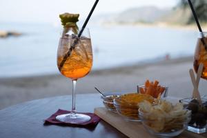 a drink in a glass on a table with snacks at Testa di Monaco Natural Beach in Capo dʼOrlando