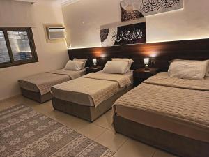 a hotel room with three beds in a room at شقة العقيق الأولى in Medina