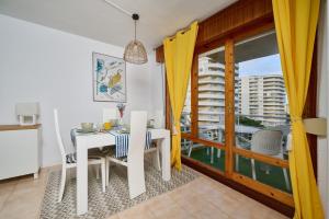 a dining room with a white table and yellow curtains at LOS RESPIGOS PLAYA in Laredo
