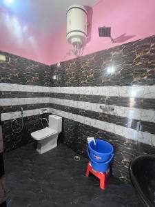 a bathroom with a toilet and a blue bucket at Navya Homestay and Restaurant in Jāmb +19 photos