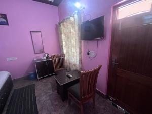 a room with a table and a tv and a bedroom at Navya Homestay and Restaurant in Jāmb