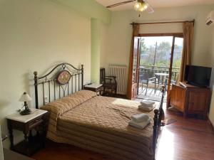a bedroom with a bed with a television and a balcony at Saily Beach Hotel in Koropi +75 photos