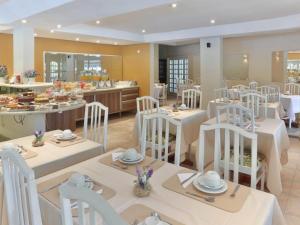 a dining room with white tables and white chairs at Amarilis Flat Apartament in Riviera de São Lourenço