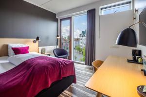 a hotel room with a bed and a desk and a window at Hotel Kolding in Kolding