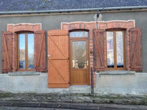 a building with wooden doors and windows on it at AUX ABORDS DU PoT BOUILLANT in Cromac +3 photos