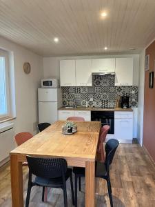 a kitchen with a wooden table and some chairs at AUX ABORDS DU PoT BOUILLANT in Cromac