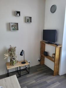 a living room with a flat screen tv and a table at AUX ABORDS DU PoT BOUILLANT in Cromac