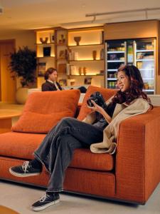 a woman sitting on a couch playing a video game at Il Leon D'Oro Bari - by Farace Hotels in Bari