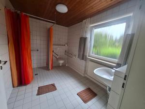 a bathroom with an orange shower curtain and a sink at Pension Sochor in Aidenbach