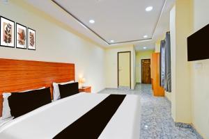 a bedroom with a large white bed with a wooden headboard at Hotel O Madlen in Hyderabad