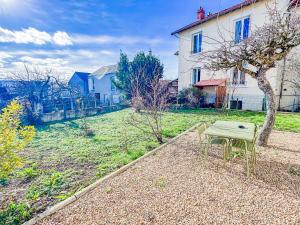 a table and a chair sitting in a yard at Grand appartement avec jacuzzi et jardin in Clermont-Ferrand