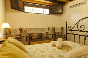 a bedroom with a bed and two chairs and a window at Cortijo La Algallumbilla in Carcabuey