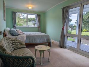a bedroom with a bed and a chair and a window at Charming homely Cherry Villa B&B with a panorama view in Paraparaumu