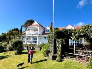a man and woman standing in front of a house with a dog at Charming homely Cherry Villa B&B with a panorama view in Paraparaumu