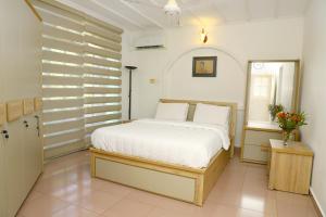 a bedroom with a white bed and a window at Dehiwala Holiday Villa in Dehiwala