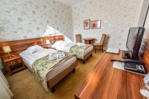 a hotel room with two beds and a desk with a computer at Wellness hotel Spark in Malacky +59 photos