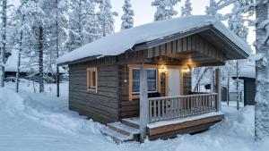 a log cabin with a snow covered roof in the snow at North Frontier Cabins in Saariselka
