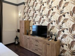 a bedroom with a tv on a dresser with a wallpaper at Mohács Korona Apartman in Mohács