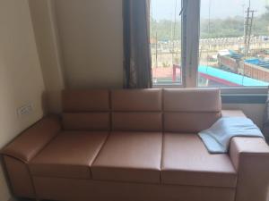 a brown couch in a room with a window at Hotel Awadh Grand in Kānpur