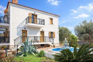 a white house with a balcony and a swimming pool at Lesvos Garden Retreats - Mountain Voyage Residences in Vatoússa