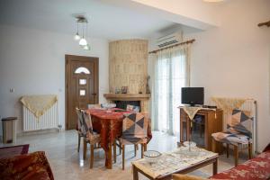 a living room with a table and chairs and a television at Lesvos Garden Retreats - Mountain Voyage Residences in Vatoússa