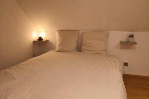a bed with white sheets and pillows in a room at Le Bollwiller Piscine Jacuzzi Vignoble in Bollwiller