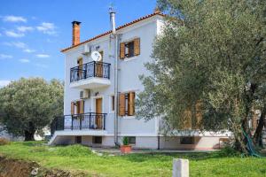 a white building with a clock on the side of it at Lesvos Garden Retreats - Mountain Voyage Residences in Vatoússa