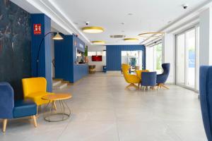 a lobby with blue and yellow chairs and a table at Aparthotel BCL Levante Beach in Benidorm +25 photos