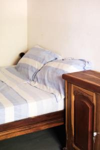 an unmade bed with a wooden table next to it at Campement Outouka in Kafountine +4 photos