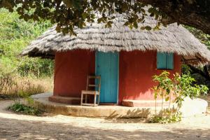 a small house with a chair in front of it at Campement Outouka in Kafountine