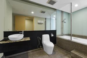 a bathroom with a toilet and a sink and a tub at Sunday Hotel Subang in Subang Jaya