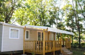 a tiny house with a porch and a deck at ZEcamping 3 étoiles avec piscine chauffée en pleine nature in Belmont-sur-Rance